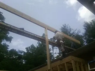 Carpenter setting a ridge beam over a new addition frame — Ice Dam Removal by Roofing Brothers in Mohrsville