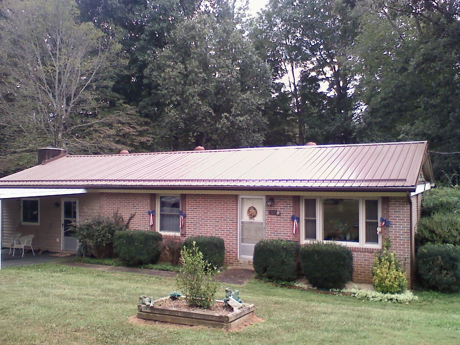 Bronze metal roof on a brick ranch home with a carport in Mohrsville
