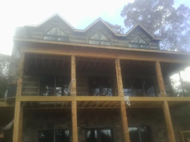Dormers and porch framing on a large log home under construction — Roof Coating work by our crew in Mohrsville