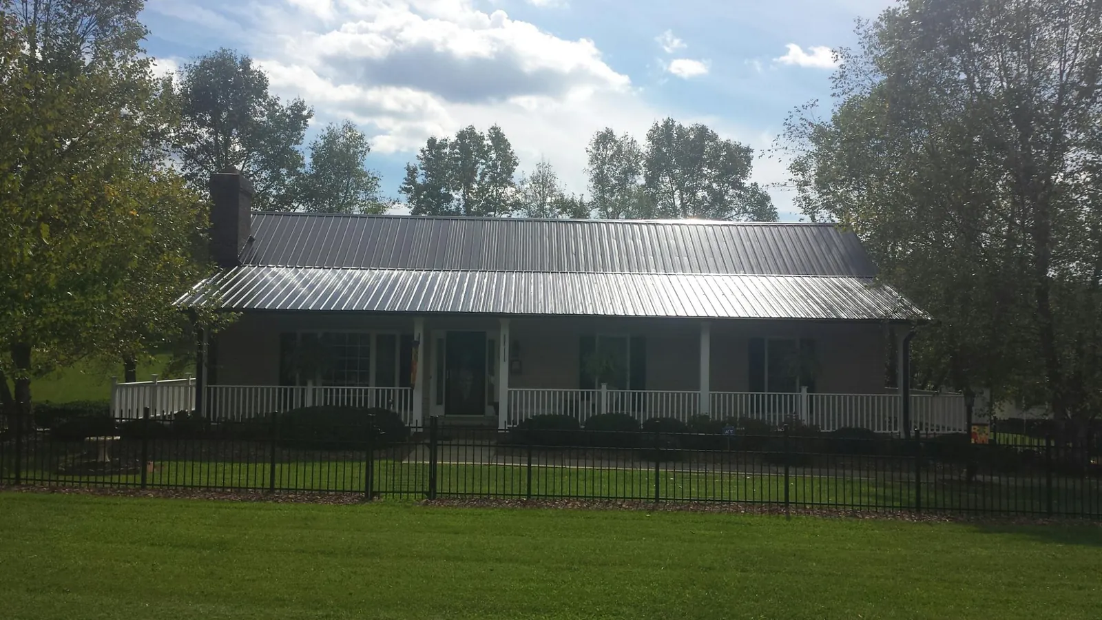 Gray metal roof on a brick ranch with a full width front porch — Gutter Guard Installation work by our crew in Mohrsville
