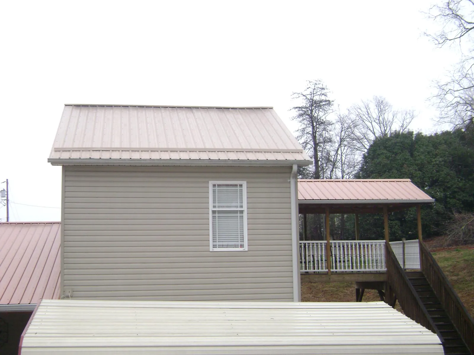 Tan metal roofs on a two story addition and attached porch, from a Roof Replacement job in Mohrsville