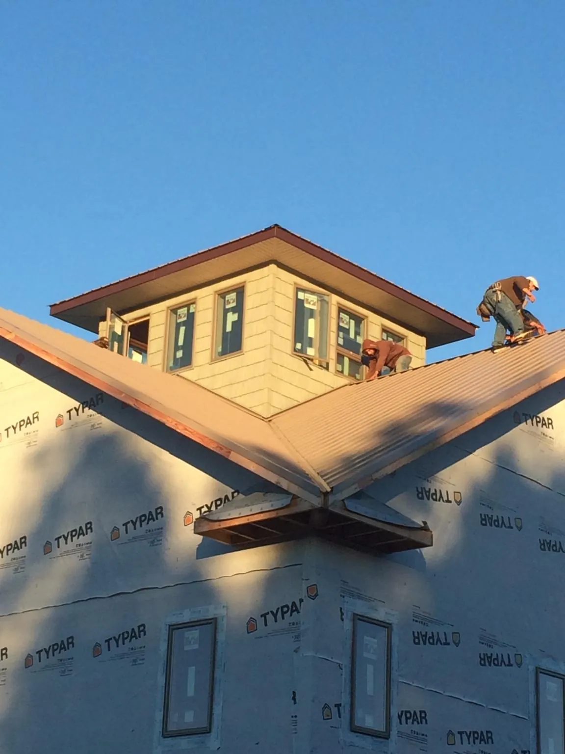 Roofers working around a rooftop cupola on a new metal roof at sunset — Roof Waterproofing in Mohrsville by Roofing Brothers